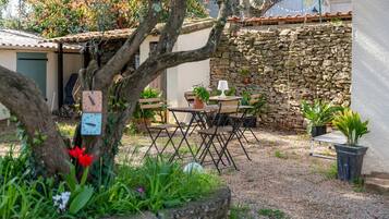Un espace extérieur aménagé dans un style rustique, avec un mur en pierre, une table en bois et des chaises.