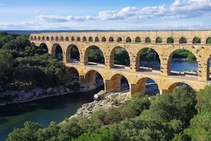 Un puente de piedra con varios arcos que cruza un río, rodeado de vegetación.