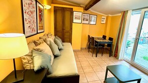 Una habitación con un sofá, una mesa, sillas, una lámpara y cuadros en la pared.
