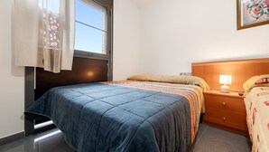 A bedroom with a bed, a nightstand, a lamp, a window with curtains, and a wall-mounted artwork. - Apartment "Deltebre Riu" with Shared Pool & Wi-Fi (Deltebre)