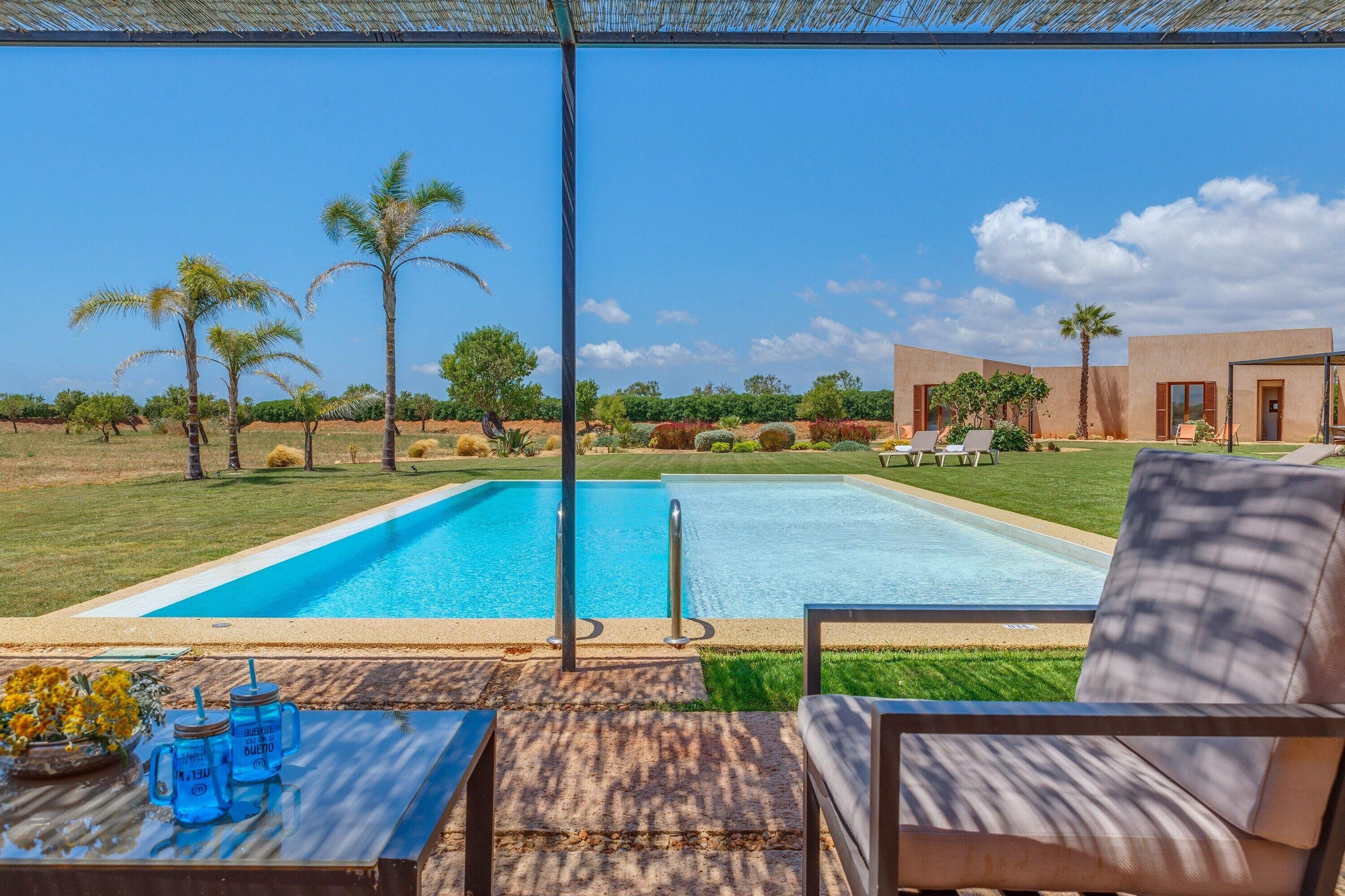 Zona de piscina con vista despejada a la piscina, sillas de descanso y un edificio de diseño moderno.