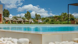 A swimming pool with lounge chairs and a clear sky.
