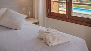 A neatly made bed with a white pillow and a folded bathrobe on it.
