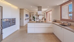 A modern kitchen with a central island, built-in appliances, and a large window.