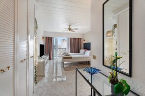 Une chambre d’hôtel équipée d’un lit, d’un bureau, d’un miroir et d’un ventilateur de plafond.