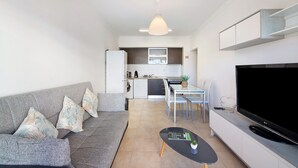 A modern living room with a grey sofa, a black coffee table, and a flat-screen TV. - Holiday Apartment "Portimão" with Mountain View, Shared Pool & Wi-Fi (Portimão)
