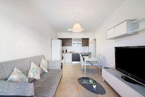 A modern living room with a grey sofa, a black coffee table, and a flat-screen TV.