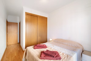 A bedroom with a bed, a wardrobe, and a bedside table.