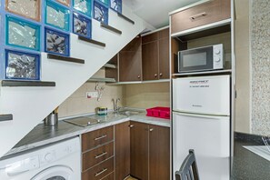 A compact kitchen with a washing machine, a microwave, and a refrigerator. - Vacation Apartment 'Dunaflor Gemelo 3' with Shared Pool, Wi-Fi and Air Conditioning (San Bartolomé de Tirajana)