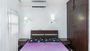 A bedroom with a bed, two bedside tables, an air conditioning unit, a wardrobe, and two wall-mounted lamps. - Vacation Apartment 'Dunaflor Gemelo 3' with Shared Pool, Wi-Fi and Air Conditioning (San Bartolomé de Tirajana)