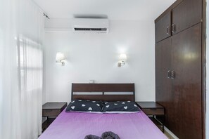 A bedroom with a bed, two bedside tables, an air conditioning unit, a wardrobe, and two wall-mounted lamps. - Vacation Apartment 'Dunaflor Gemelo 3' with Shared Pool, Wi-Fi and Air Conditioning (San Bartolomé de Tirajana)