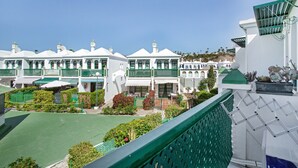A row of white buildings with green accents, a green roof, and a clear sky. - Vacation Apartment 'Dunaflor Gemelo 3' with Shared Pool, Wi-Fi and Air Conditioning (San Bartolomé de Tirajana)