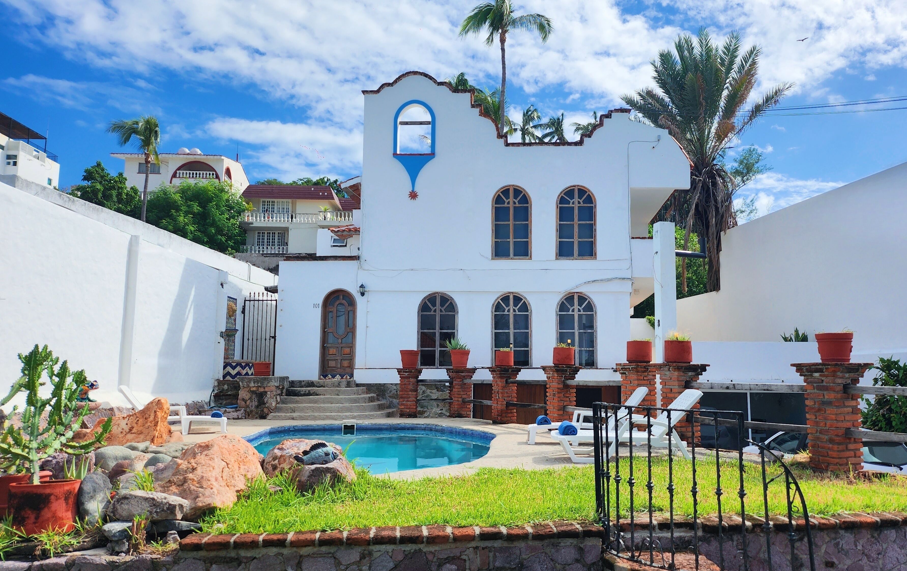 A white building with arched windows and a pool area.