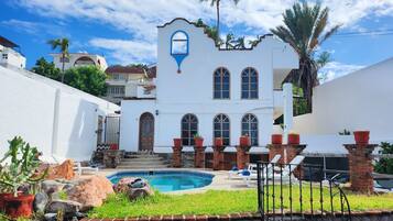 A white building with arched windows and a pool area.