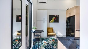 A modern kitchen with white cabinets, a black refrigerator, and a small dining area with a table and chairs. - Olive Apartments (Miami)