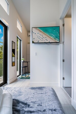 A modern living room with a large TV mounted on the wall, a sofa, and a patterned rug. - Olive Apartments (Miami)