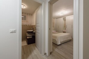 A bedroom with a bed, a bedside table, a mirror, and a wardrobe.