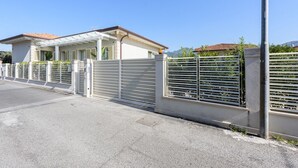 Ein durch eine Mauer geschütztes Anwesen mit überdachter Terrasse, befestigter Auffahrt und Bergblick.