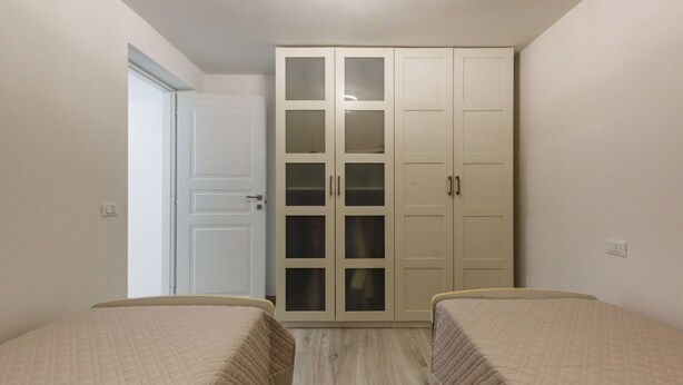 Ein Schlafzimmer mit zwei Betten, einem Kleiderschrank und einer Tür zu einem anderen Raum.