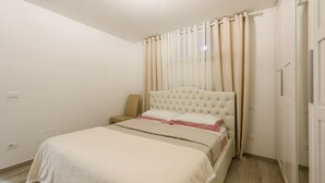 Ein Schlafzimmer mit Bett, Vorhängen, Nachttisch und einer Steckdose.