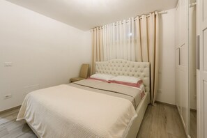 Une chambre à coucher avec un lit, des rideaux, une table de chevet et une prise électrique au mur.