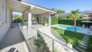 Ein modernes Haus mit Glasbalkon, Swimmingpool und einem gepflegten Garten.