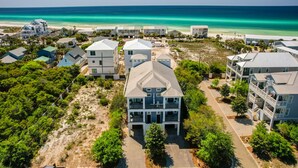 Un quartier résidentiel situé sur la côte, composé de plusieurs maisons à deux étages, dont certaines sont dotées de balcons, et avec une plage en arrière-plan.