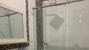 Un baño con cabina de ducha de vidrio, inodoro, lavabo y espejo.