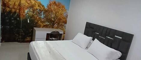 A bedroom with a bed, a nightstand, a wall-mounted air conditioner, and a mural of autumn trees.
