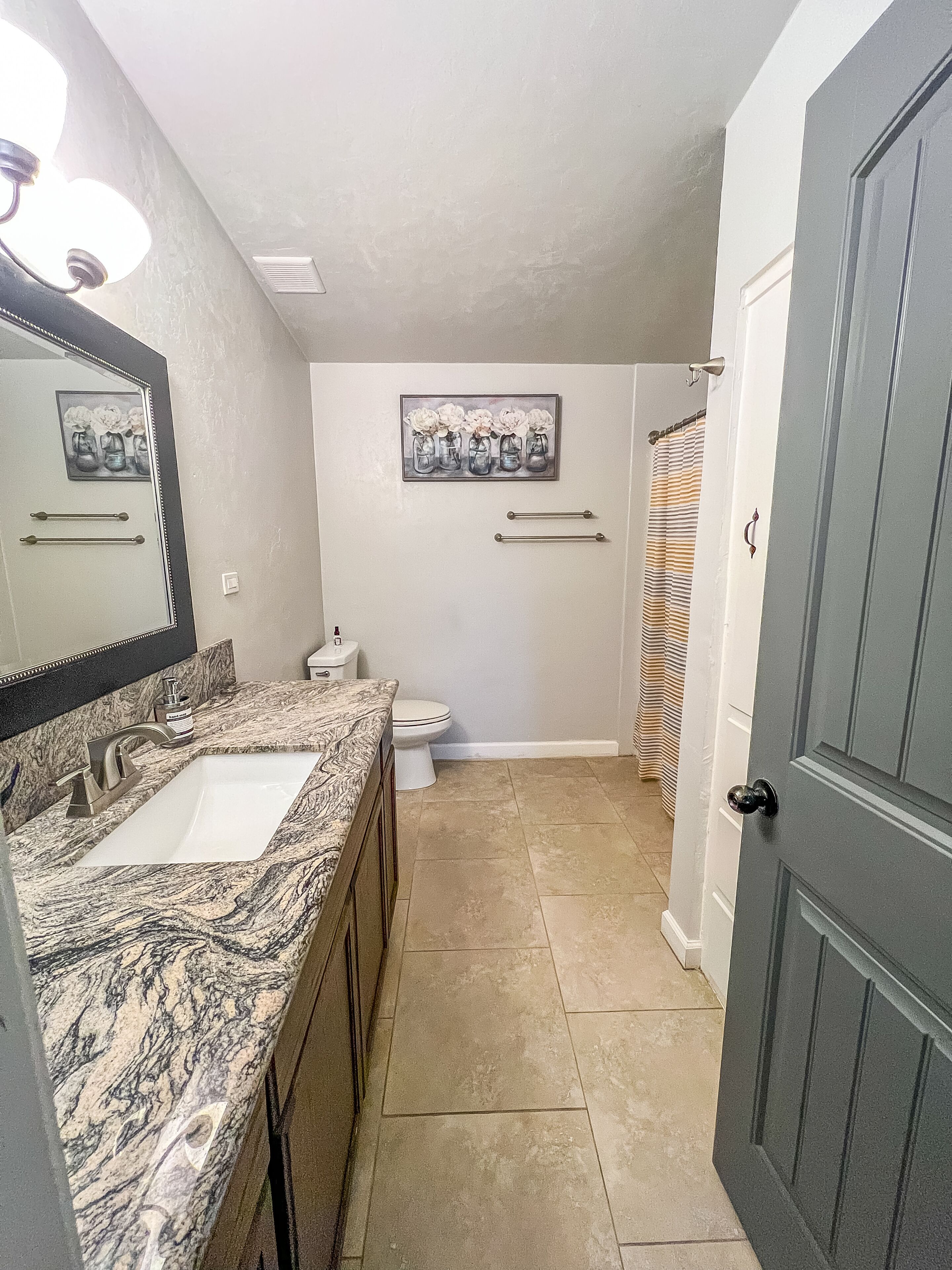 A bathroom with a marble sink, a toilet, and a shower curtain.