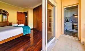 Ein Schlafzimmer mit Bett, Bad und einer durch eine offene Tür erkennbaren Küchenzeile.