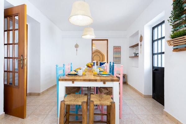 A dining area with a wooden table, chairs, and hanging lights.