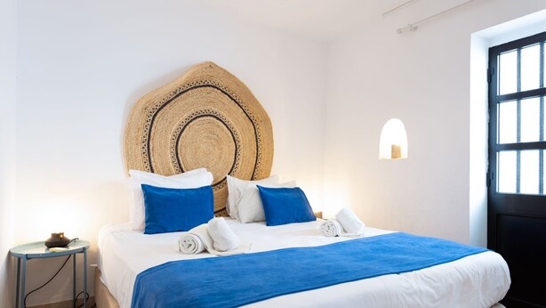 A neatly made bed with a blue and white bedspread, a woven headboard, and a bedside table with a lamp. - #197 Casa Gili by Home Holidays (Albufeira)
