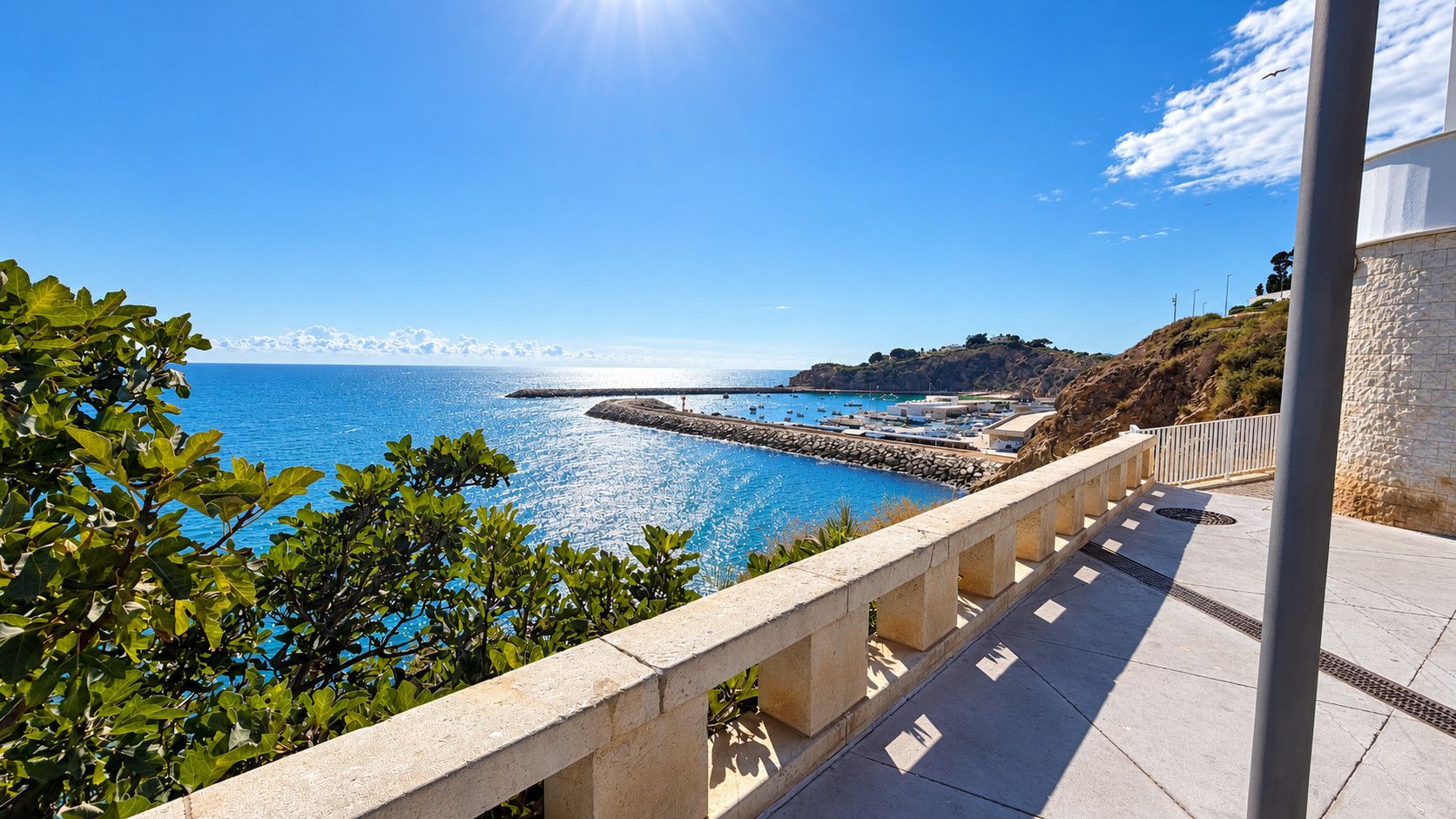 A coastal view with a clear sky, a stone pathway, and a rocky landscape.