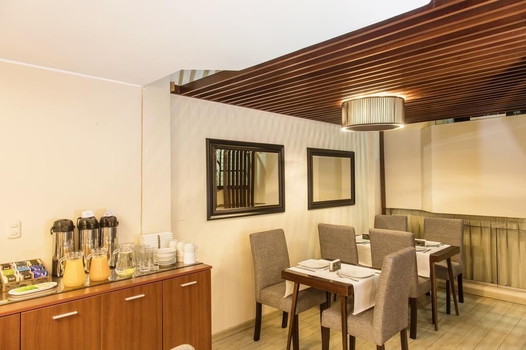 Zona pranzo con soffitto in legno, banco buffet con cibo e bevande, e tavolo imbandito per sei persone.