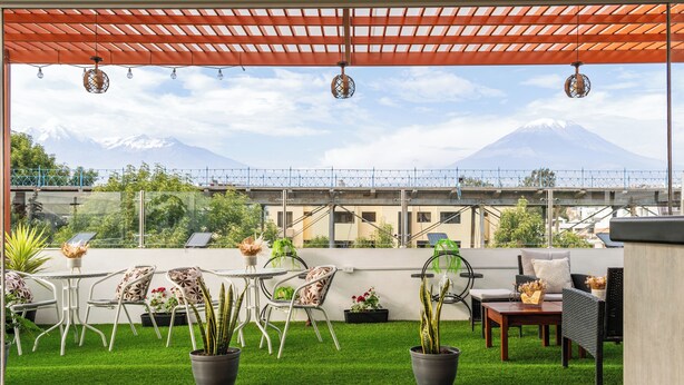Une terrasse sur le toit offrant une vue sur une montagne, avec du gazon synthétique vert et du mobilier d’extérieur.