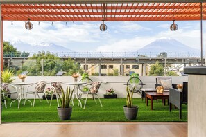 Une terrasse sur le toit offrant une vue sur une montagne, avec du gazon synthétique vert et du mobilier d’extérieur.
