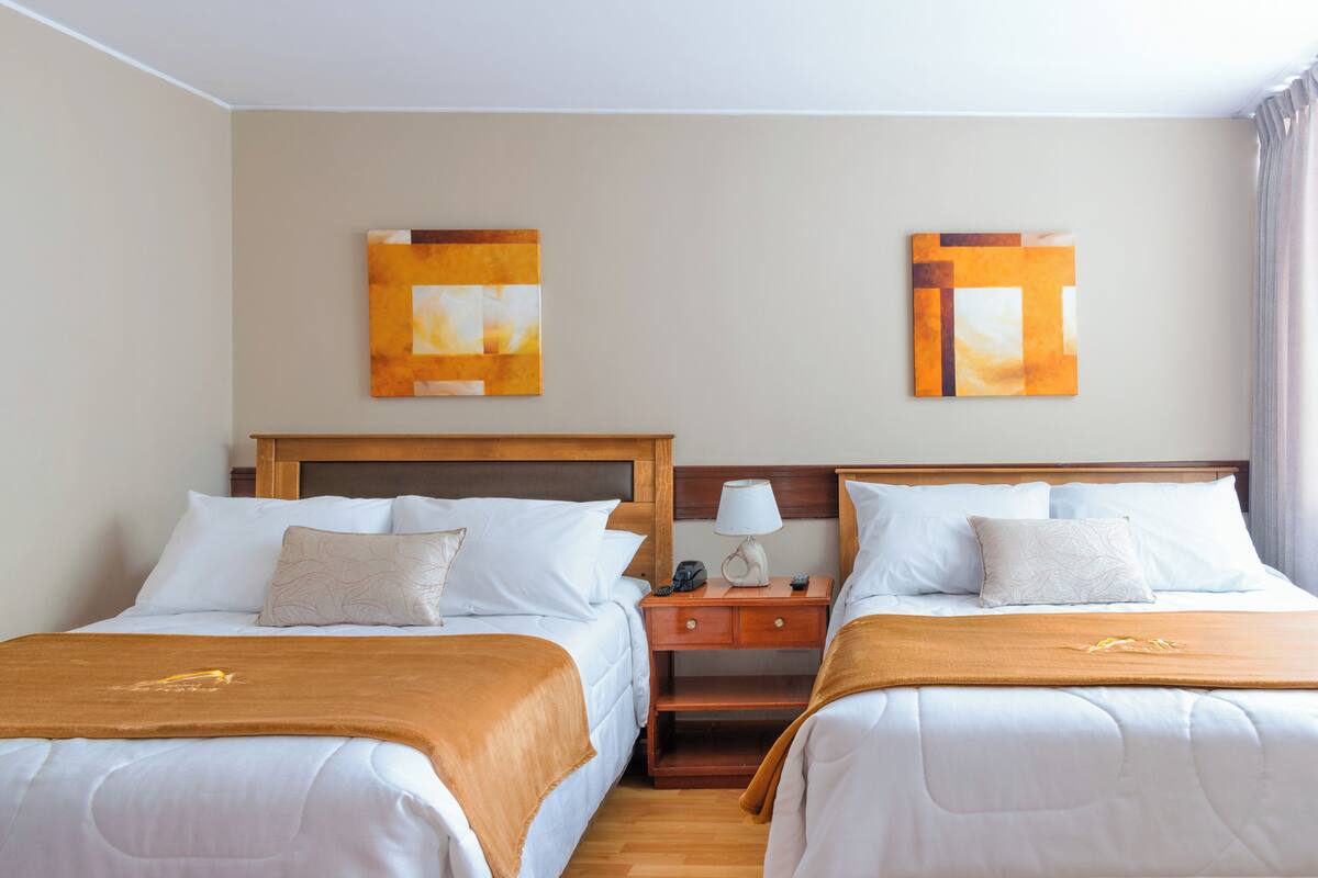 Ein Hotelzimmer mit zwei Betten, einem Nachttisch und Bildern an den Wänden.