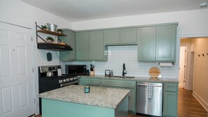 A kitchen with teal cabinets, a granite countertop, stainless steel appliances, and a wooden island. - Double Everything - Sleeps 13

 (Fort Worth)