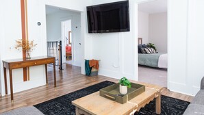 A modern living room with a wooden coffee table, a flat-screen TV mounted on the wall, and a sofa. - Double Everything - Sleeps 13

 (Fort Worth)