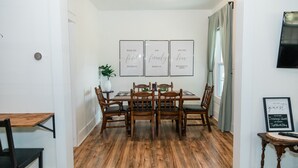 A dining area with a wooden table and chairs, framed inspirational quotes on the wall, and a potted plant. - Double Everything - Sleeps 13

 (Fort Worth)