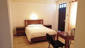 A bedroom with a bed, bedside tables, a desk, and a chair. - Hotel Cesare (Uyuni)