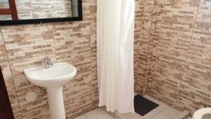 A bathroom with a pedestal sink, a shower curtain, and a toilet. - Hotel Cesare (Uyuni)