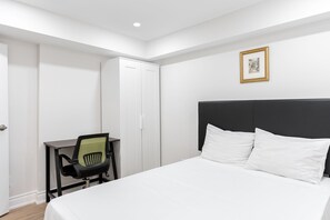 Une chambre d’hôtel comprenant un lit, un bureau avec une chaise, une armoire et un tableau encadré au mur.