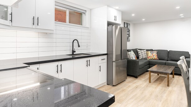 A modern kitchen with white cabinets, a black countertop, and a stainless steel refrigerator. - Stunning 2BR Lower Level Unit

 (Richmond Hill)