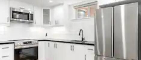 Een moderne keuken met witte kastjes, roestvrijstalen apparatuur en een koelkast met dubbele deuren.