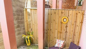 A patio area with wicker furniture, a round table, and a wooden fence. - Governors Apartment -  2 bedroom  - Steps to FQ (New Orleans)