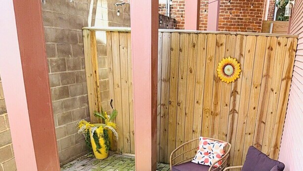 Un patio con mobiliario de mimbre, una mesa redonda y una cerca de madera.