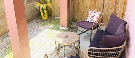 A patio area with wicker furniture, a round table, and a wooden fence.