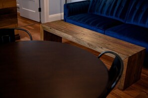 A wooden table and a blue sofa in a room with wooden flooring. - Governors Apartment -  2 bedroom  - Steps to FQ (New Orleans)